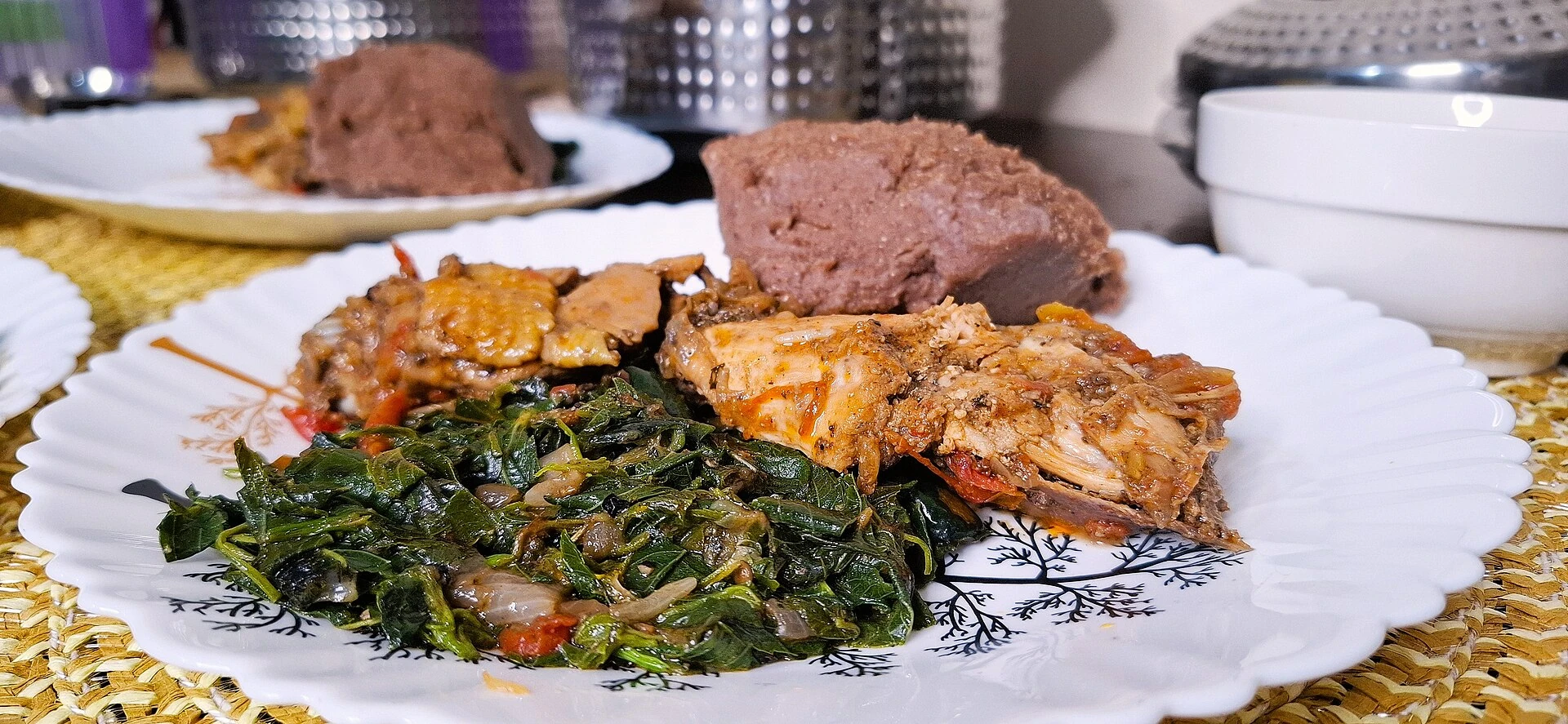 Kenyan meal with chicken, vegetables and brown ugali